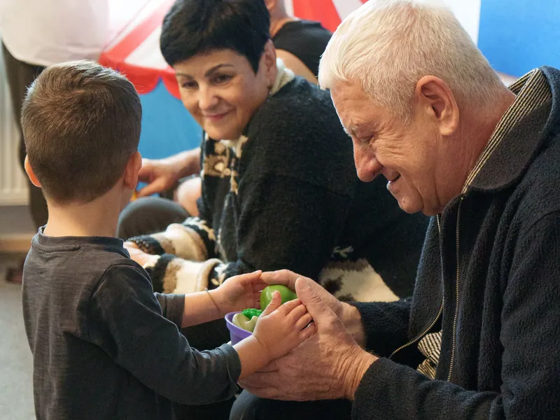 A grandfather and grandmother playing with a child at a school family event
