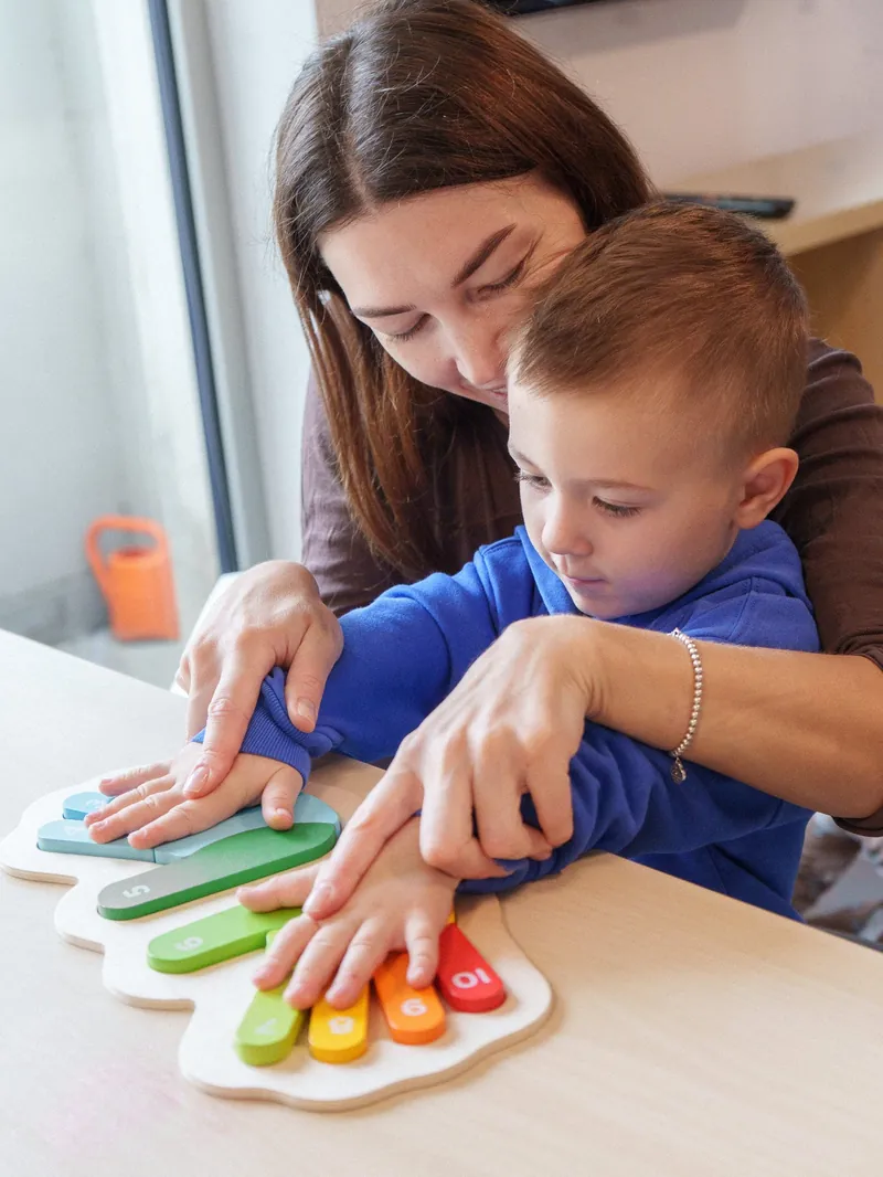 A teacher guiding a child's hands on a counting puzzle