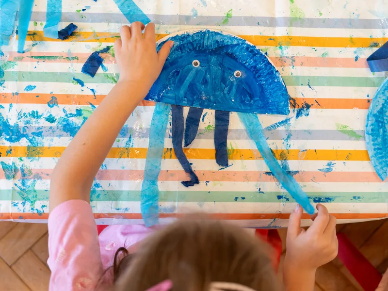 A child painting a jellyfish at the art table