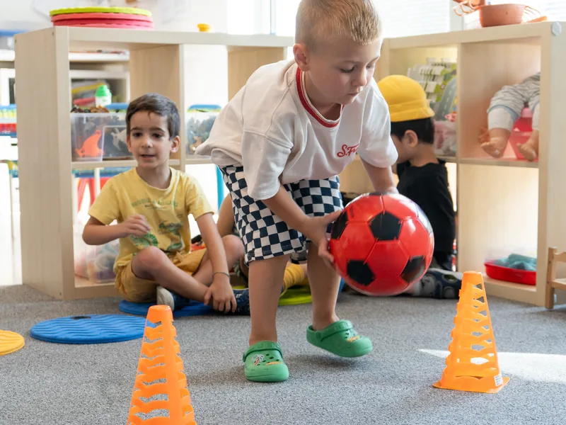 A boy dribbling a ball through cones in the indoor gym