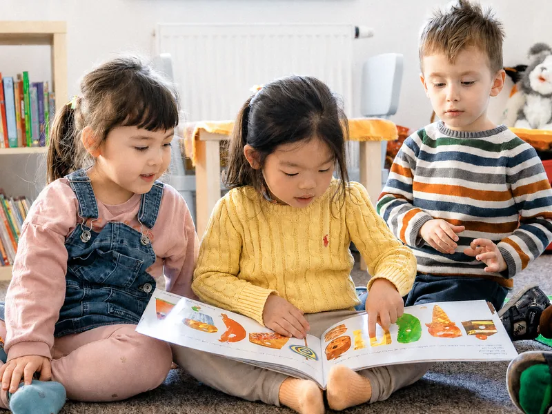 Preschool children reading a picture book together