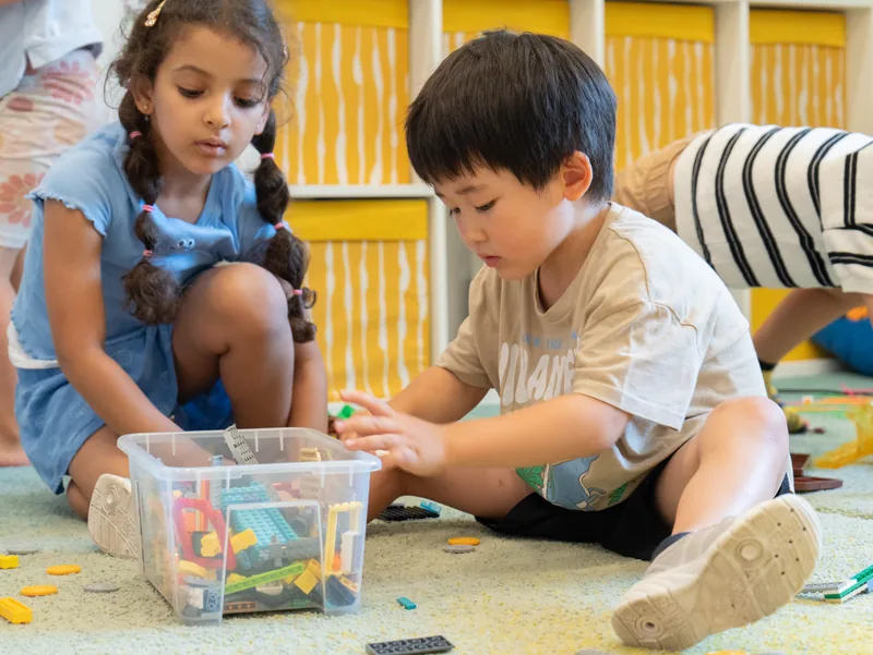 Children exploring a bin of building toys together
