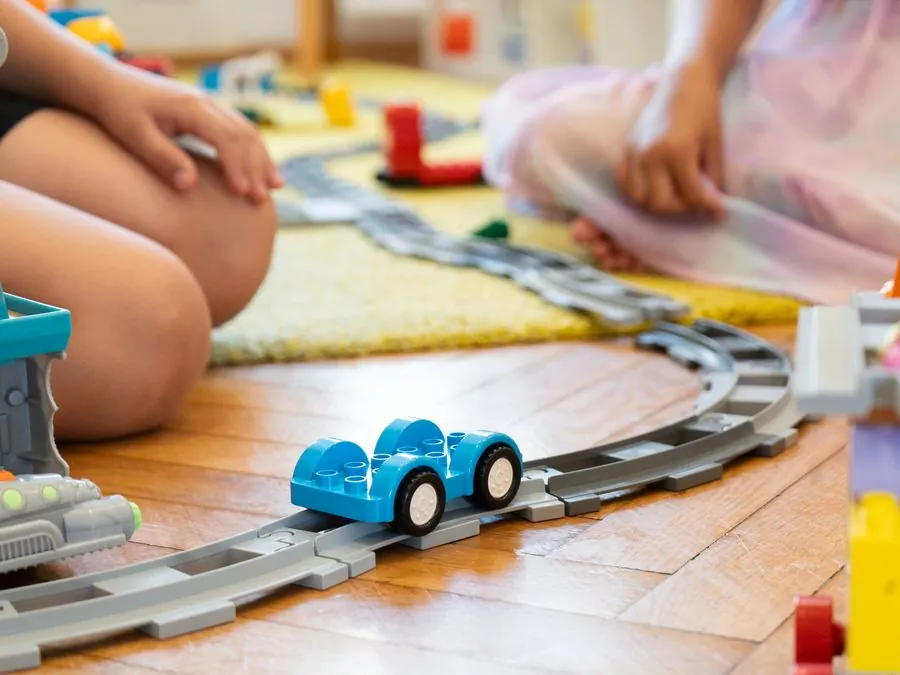 Young children playing with a train set on the classroom floor