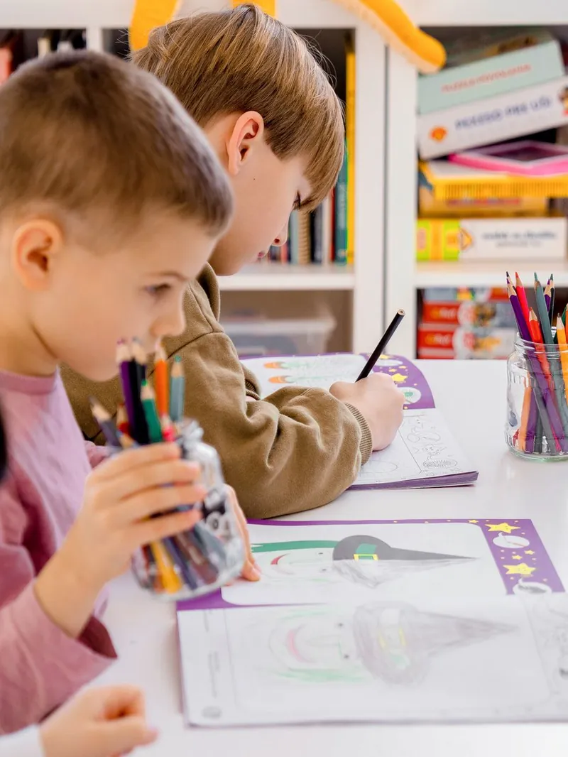 Kindergarten boys practicing writing at their desks